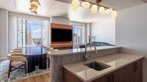 A modern kitchen with a central island, a built-in oven, and a large window offering a city view.