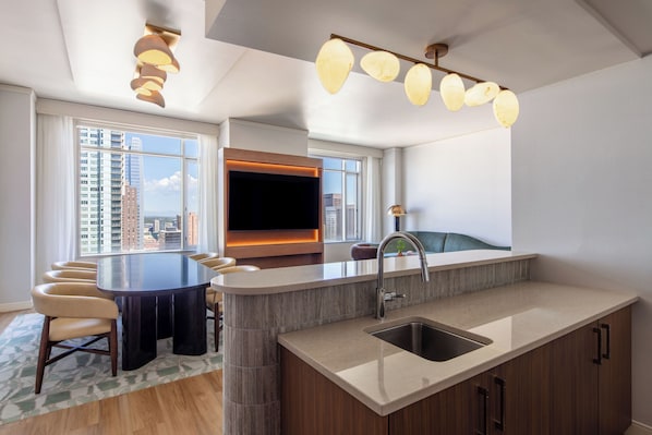 A modern kitchen with a central island, a built-in oven, and a large window offering a city view.