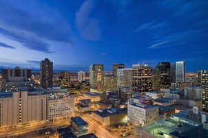 A cityscape at dusk with illuminated buildings and a clear sky.