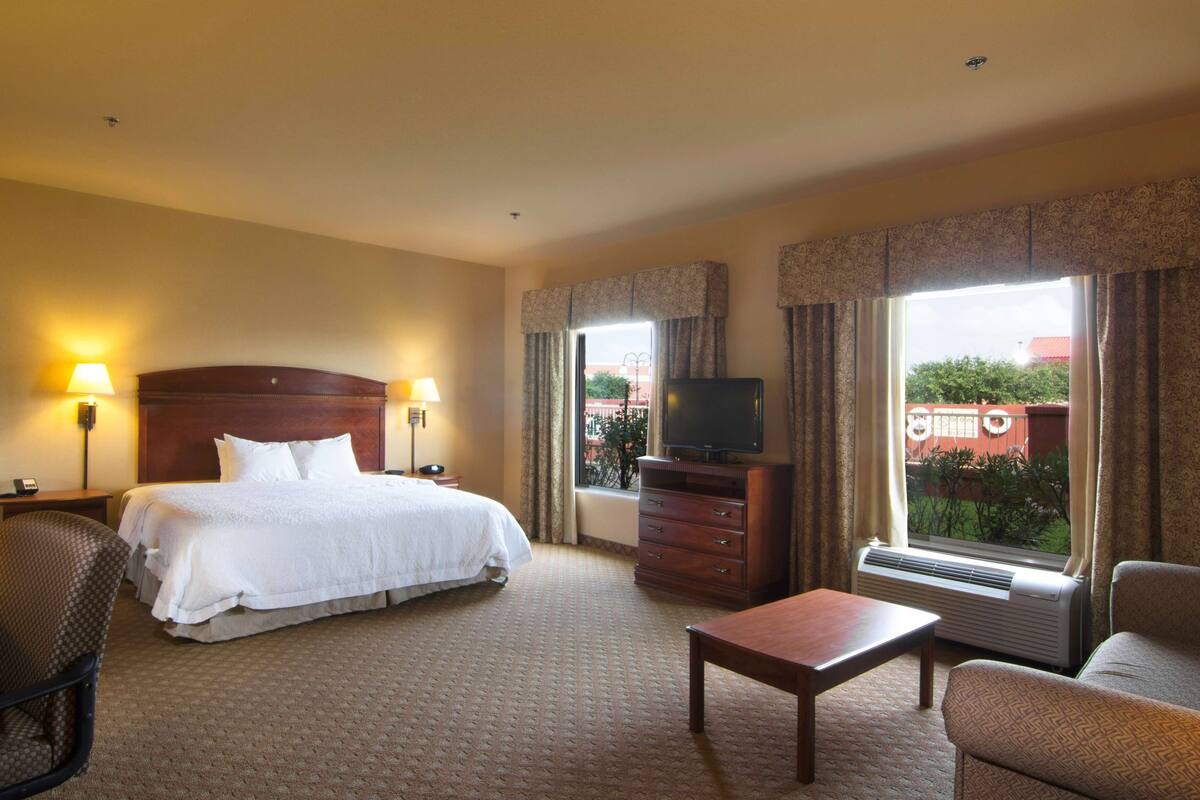A hotel room with a bed, a TV, a desk, a chair, and a dresser.