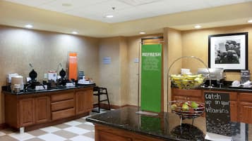 A breakfast area with a waffle maker, coffee machine, and a sign indicating a breakfast area.