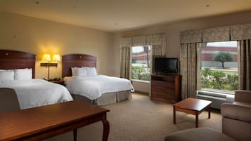 A hotel room with two beds, a TV, a desk, and a chair.