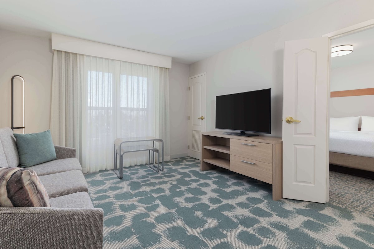 Een hotelkamer met een bank, een televisie, een bed en een deur.