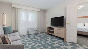 Habitación de hotel con sofá, televisión, cama y puerta.