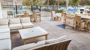 Eine Außenpatio mit Pool, Grill und Sitzbereich.