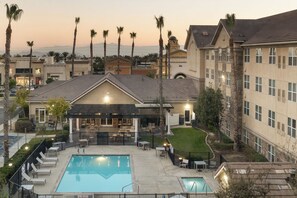 Un hôtel doté d’une piscine, d’un espace extérieur aménagé et de palmiers.