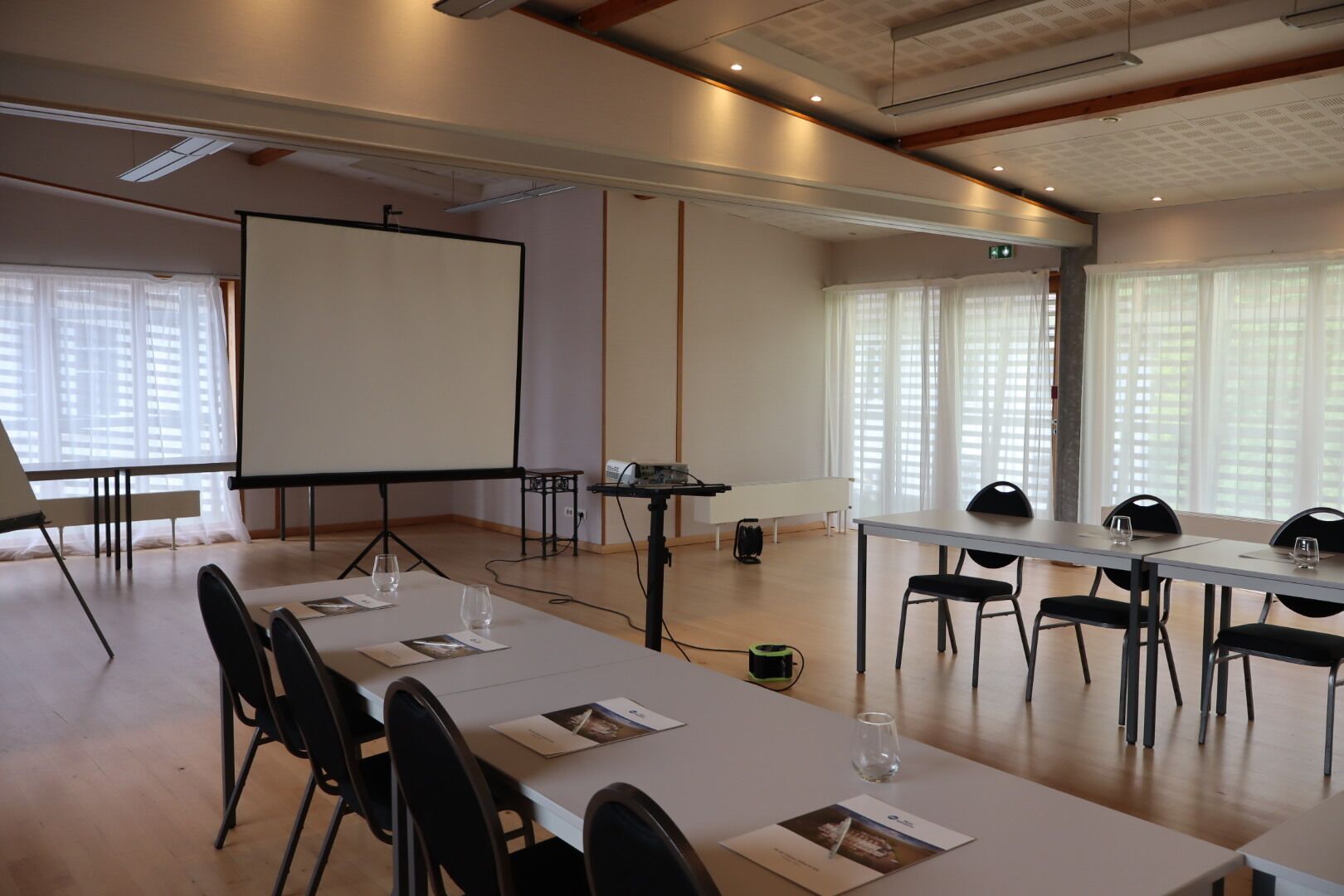 Una sala de conferencias con pizarra, proyector y mesas con sillas.