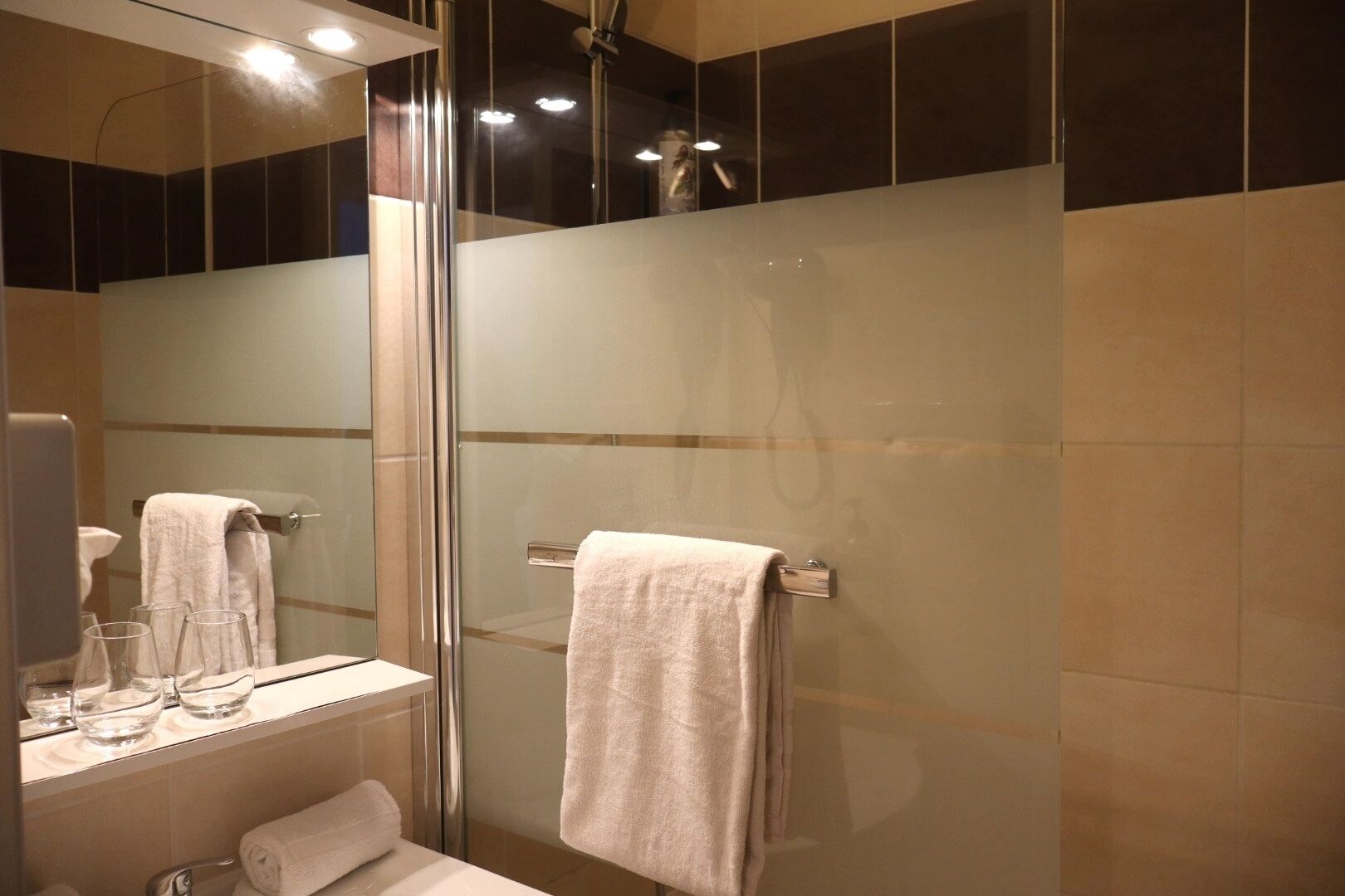 A modern bathroom with a glass shower enclosure, a vanity with a mirror, and a towel rack.