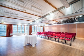 Meetings and presentations take place in this spacious room with a high ceiling, long table, and comfortable chairs.