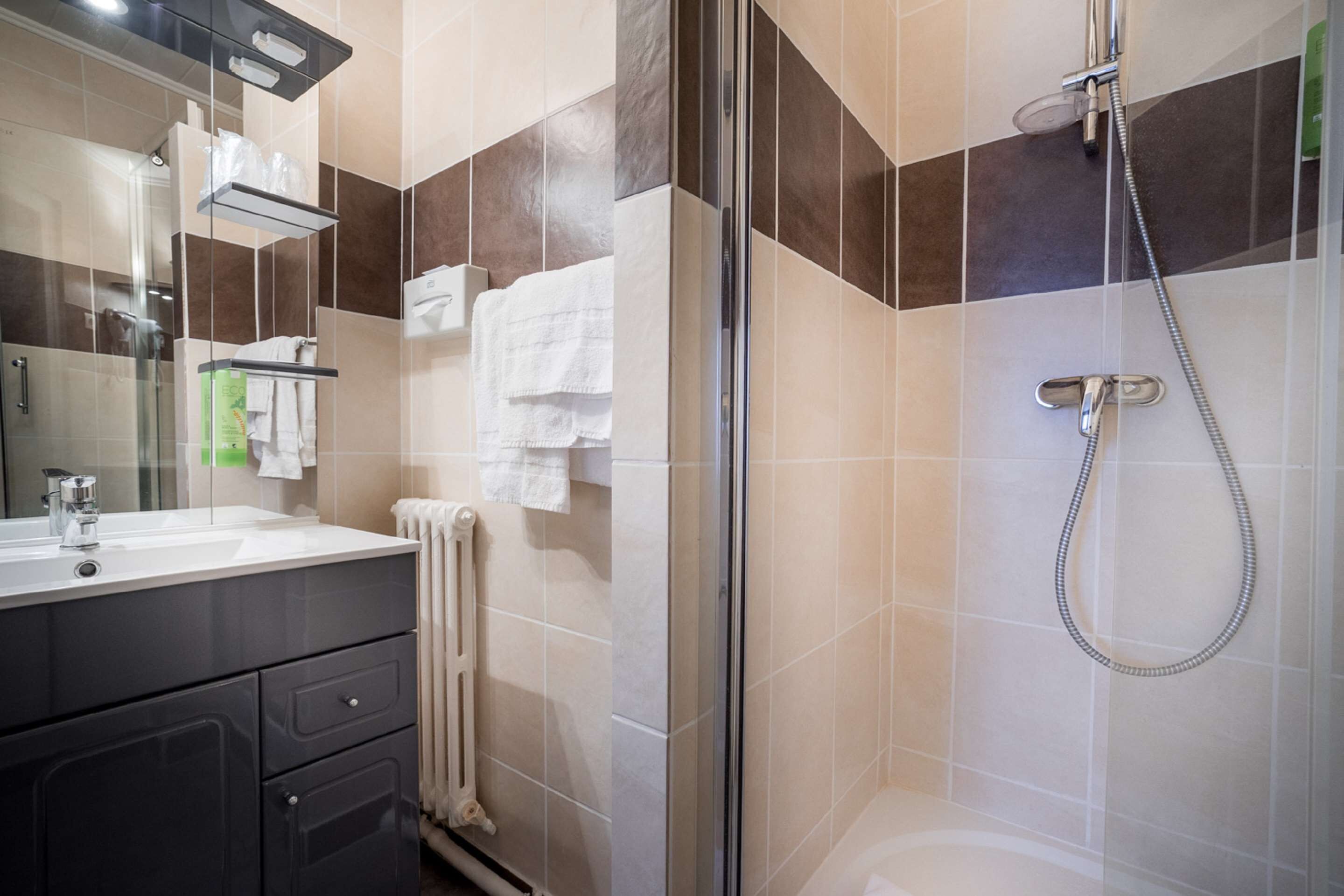 A modern bathroom with a glass-enclosed shower, a white sink, and a towel rack.