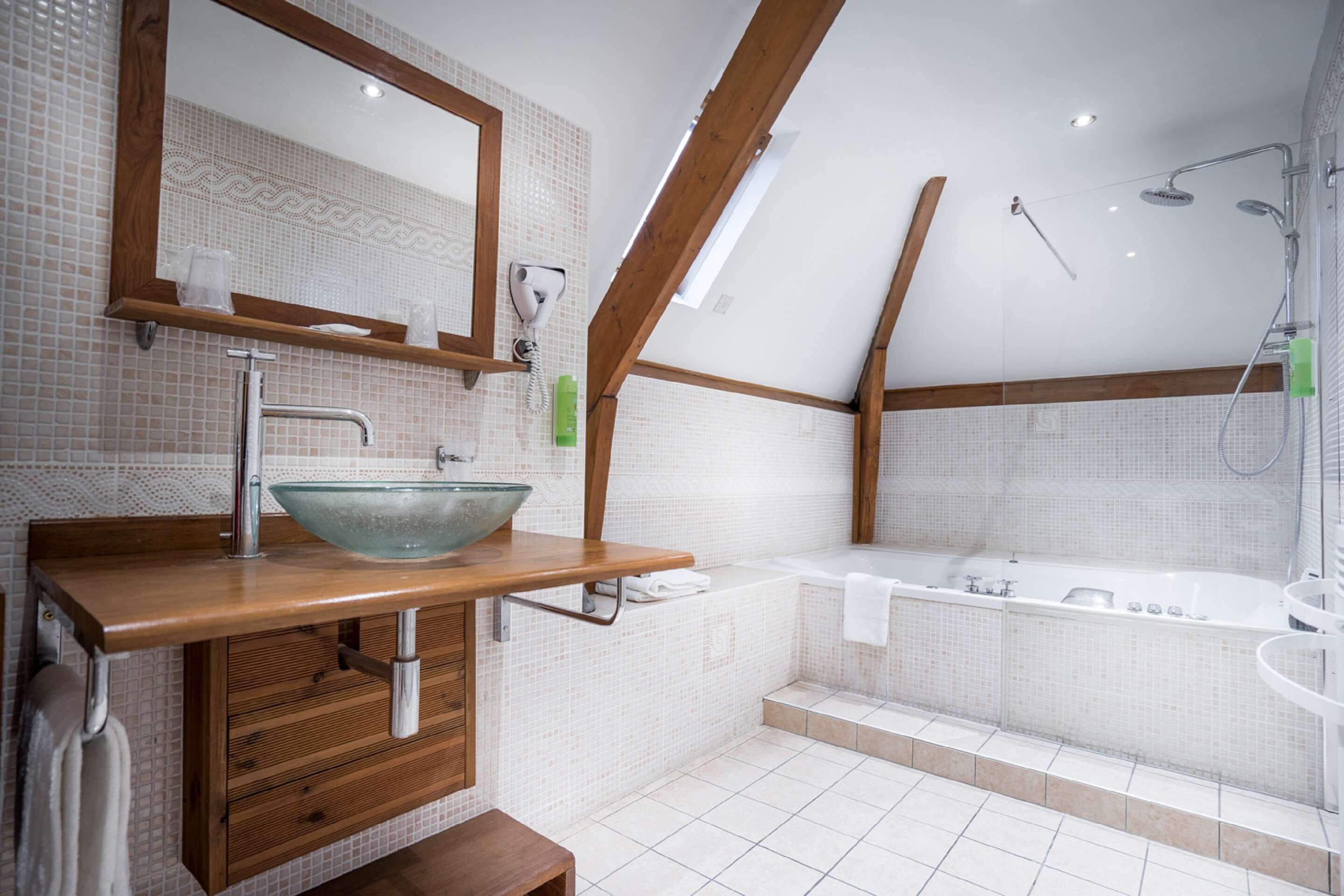 A modern bathroom with a wooden vanity, a glass bowl sink, a large mirror, a bathtub, and a shower with a glass enclosure.