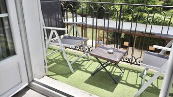 A balcony with a metal railing, a small table, and two chairs.