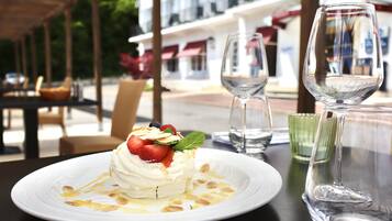 Un dessert servi sur une assiette blanche, accompagné d’un verre d’eau et d’un verre à vin, le tout posé sur une table.