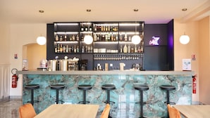 A bar area with a marble countertop, multiple stools, and a variety of bottles and glasses.