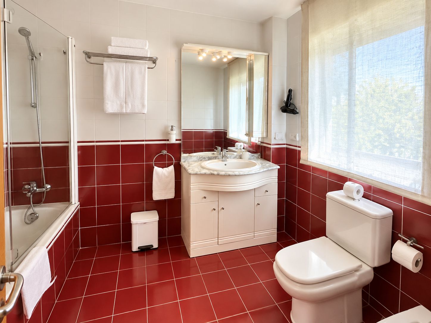 Un baño con ducha, inodoro, lavamanos y espejo.