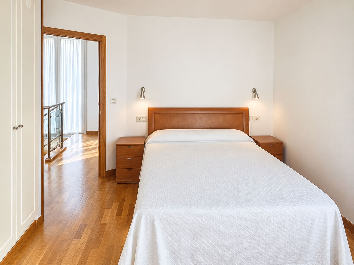 Un dormitorio con cama de madera, mesitas de noche y vistas a un balcón.