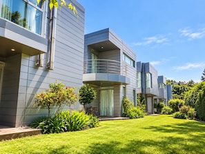 A modern multi-story residential building with a flat roof, large windows, and a well-maintained lawn. - Pazo do Río (Oleiros)