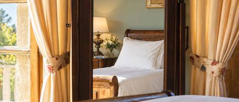 Une chambre à coucher avec un lit en bois, une table de chevet, une lampe et une fenêtre avec des rideaux.