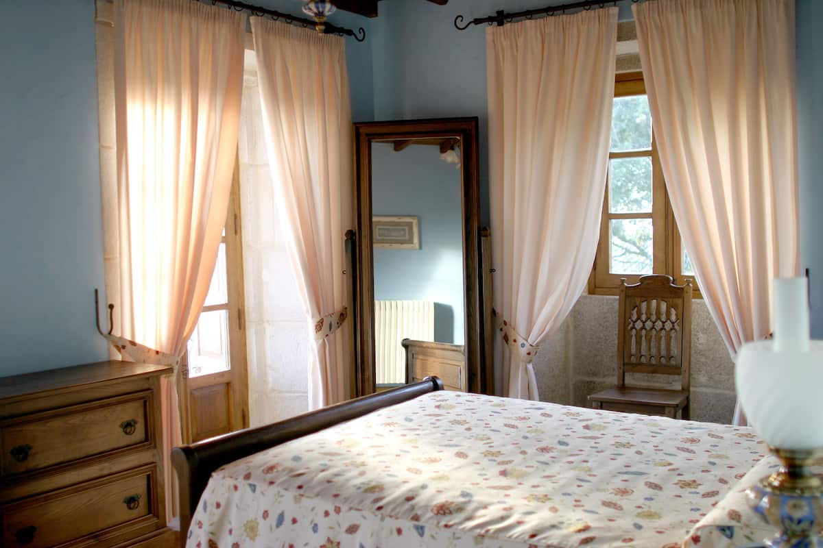 A bedroom with a bed, wooden dresser, and a chair.