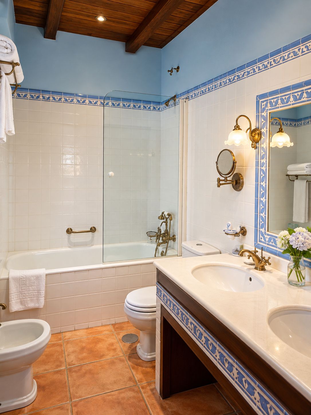 Un baño con bañera, inodoro y lavamanos, con azulejos azules y blancos y accesorios de latón.