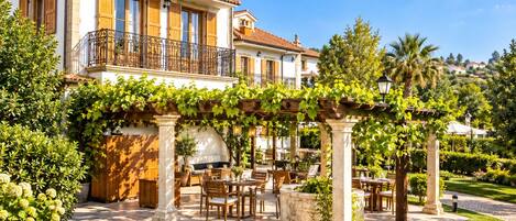 A villa with a patio area, outdoor seating, and a pergola covered with vines.