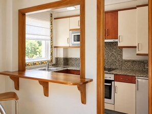 A kitchen with a wooden countertop, a sink, a microwave, and cabinets. - Pazo do Río (Oleiros)