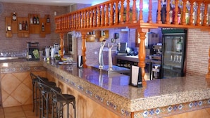 Zona de bar amb un taulell, tamborets i una varietat de garrafes.
