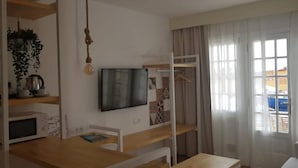 Una cuina moderna amb microones, un llum penjant i un televisor fixat a la paret.
