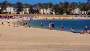Una platja amb gent que pren el sol i nedant.