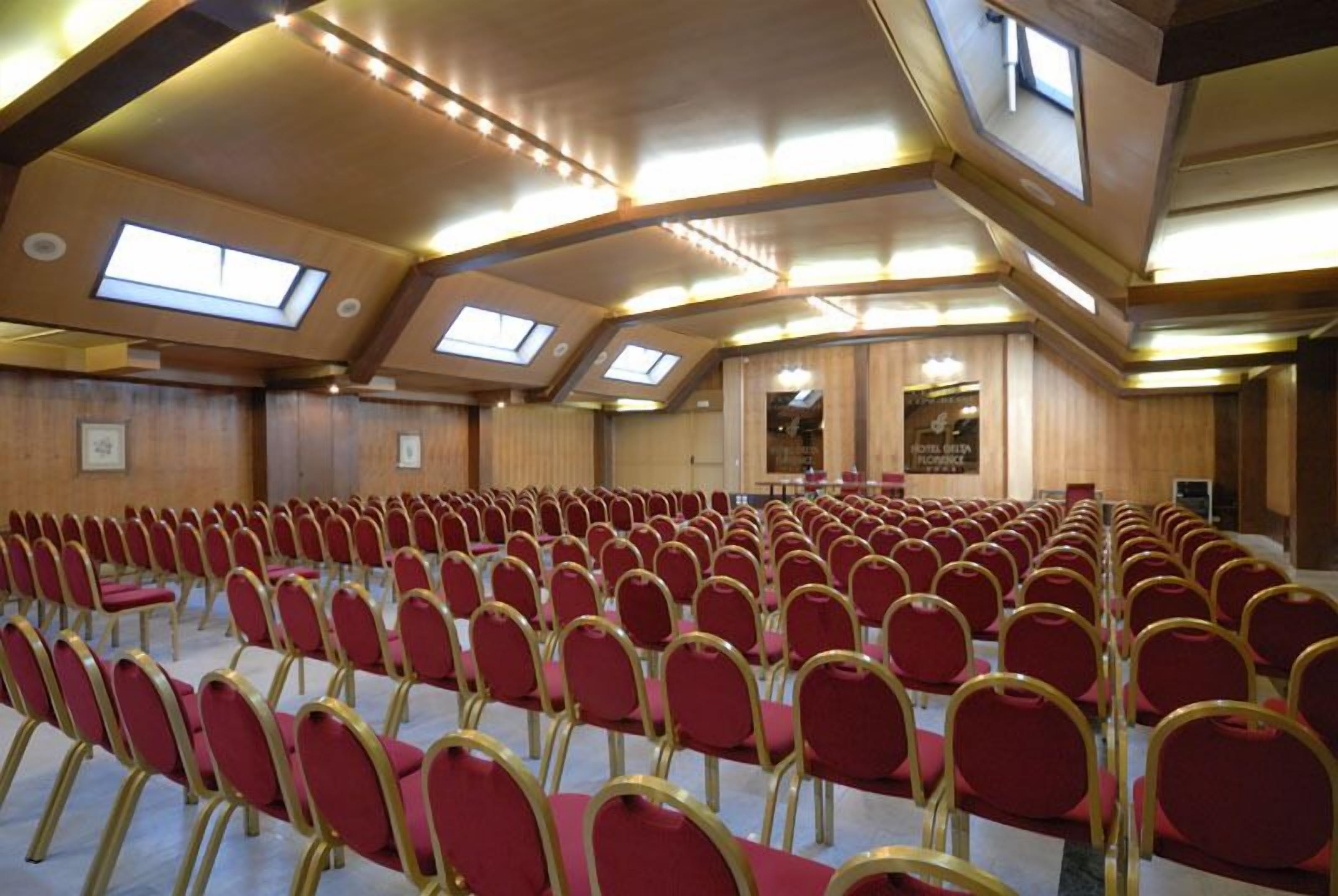 A conference room with rows of red chairs, skylights, and wooden paneling.