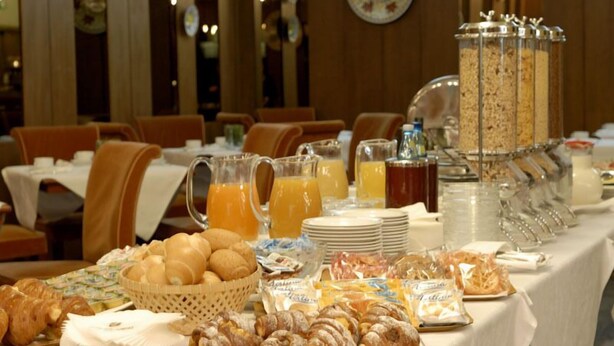 Un bufé de desayuno con pasteles, jugos y barritas de cereal.