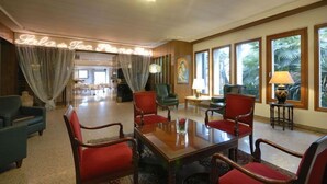Un hall de hotel con una gran mesa de madera, sillas rojas y un letrero de neón que dice "Bula Tea House".