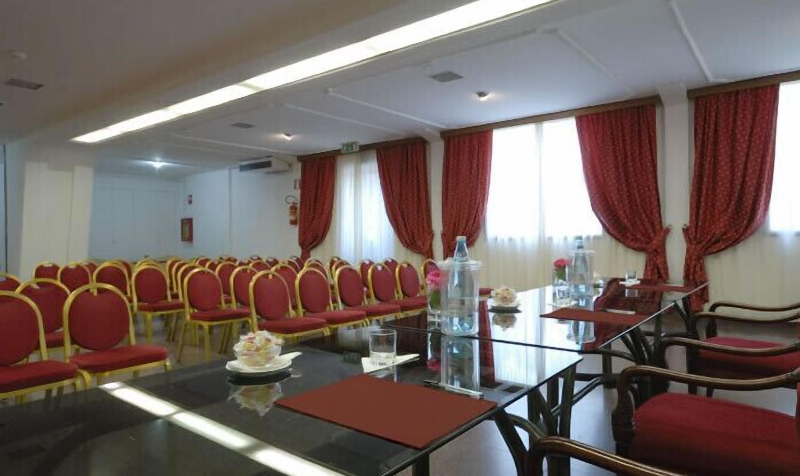 A conference room with a long table, red chairs, and a glass partition.