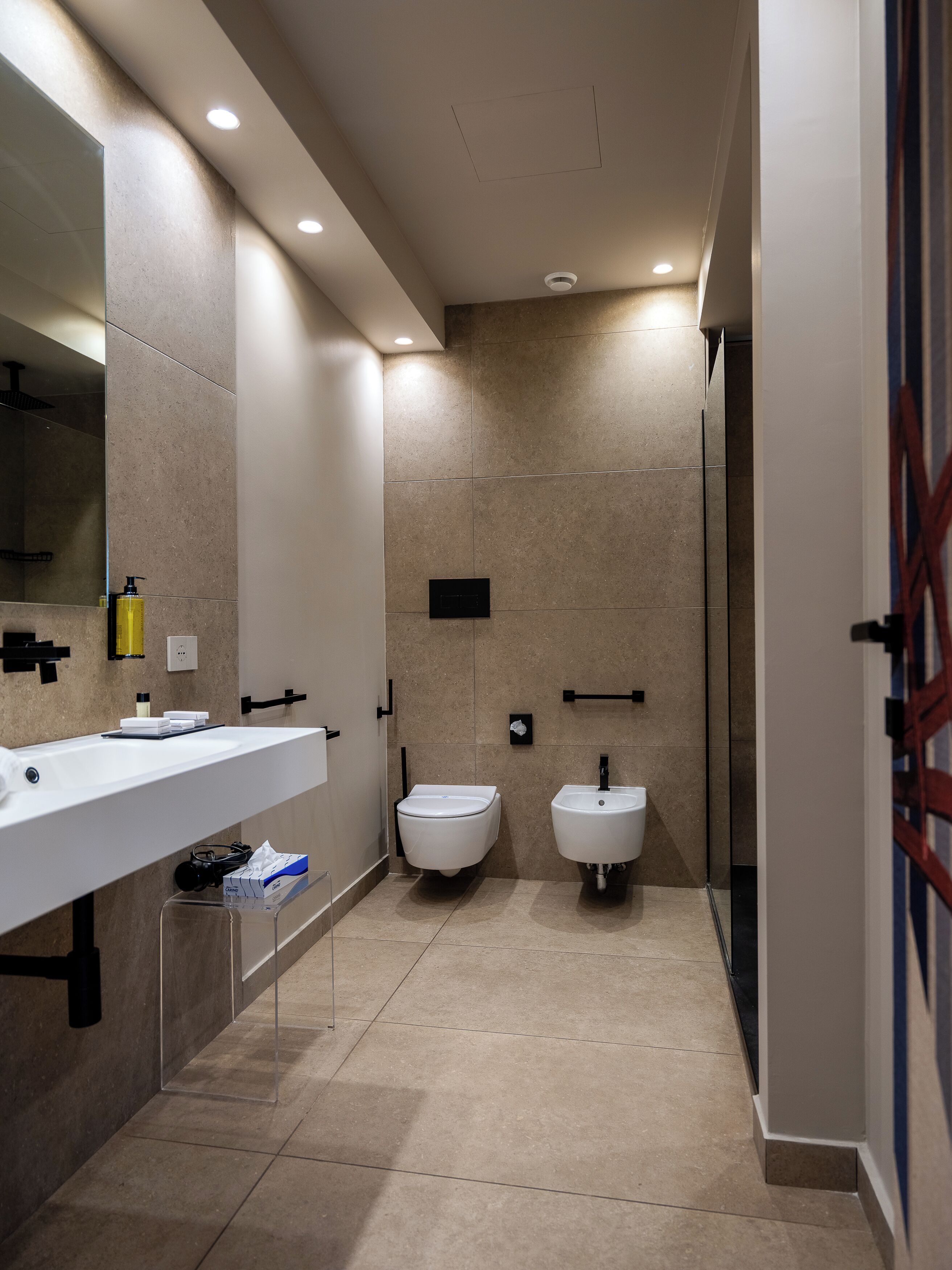 Une salle de bain moderne dotée d’un grand miroir, de deux lavabos, d’un bidet et d’un espace douche.