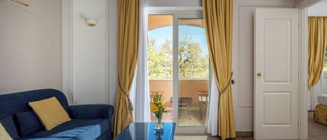 Una habitación con un sofá azul, una mesa de centro de vidrio y una puerta que da a un espacio exterior.