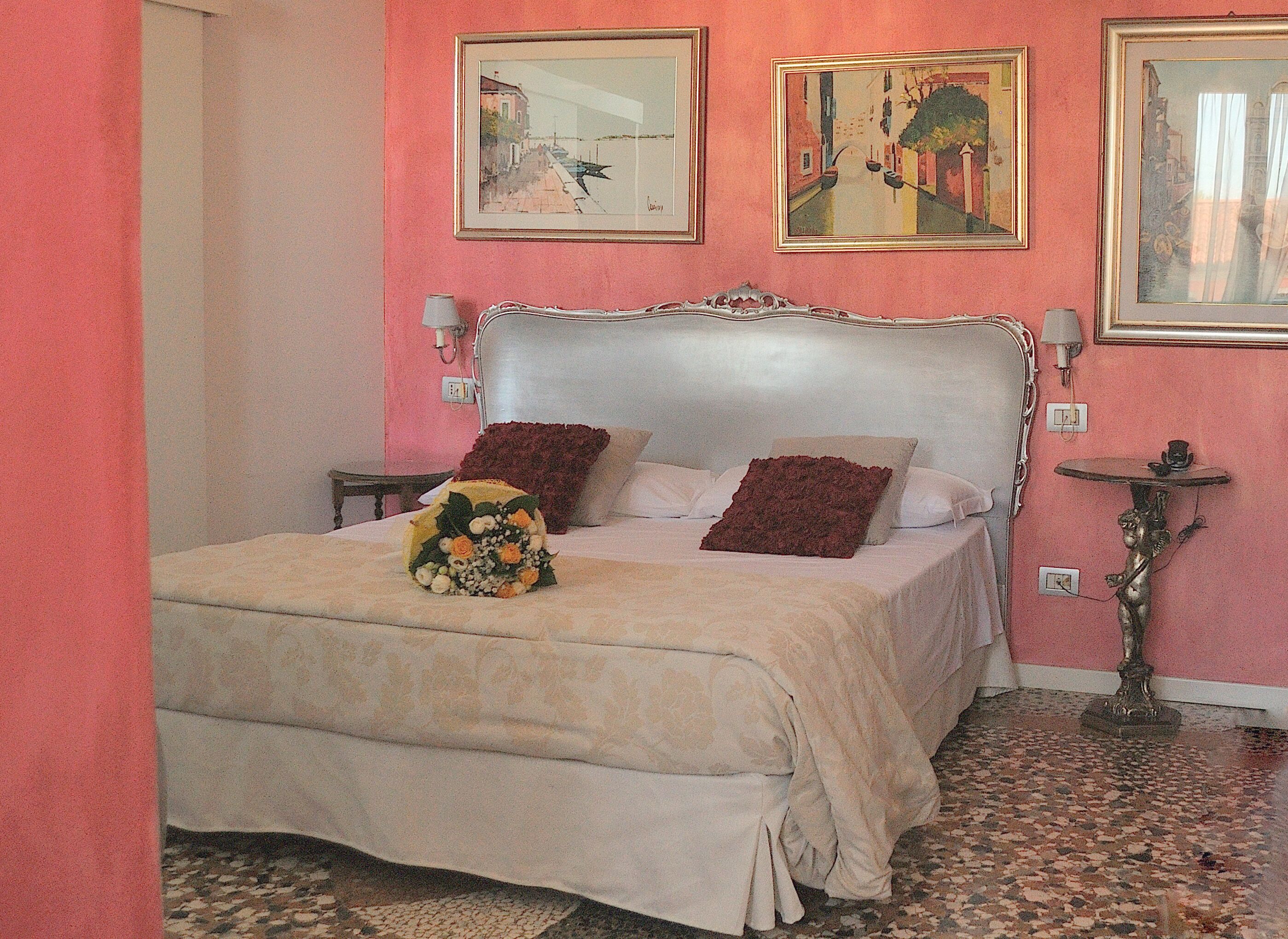 A bedroom with a large bed, a bedside table, and a small table with a lamp.