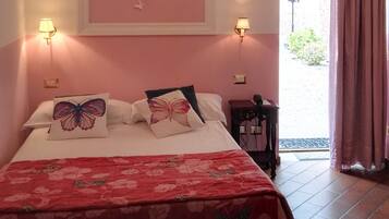 Un dormitorio con cama, almohadas con motivos de mariposas, pared rosa decorada con mariposas, lámpara de araña y ventana con cortinas.