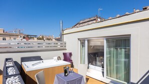 A rooftop terrace with a table set for two, a hot tub, and a large sliding glass door. - Hotel Castellino Roma (Rome)