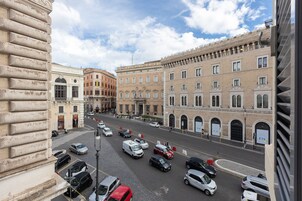 A street view with parked cars, historic buildings, and a clear sky.