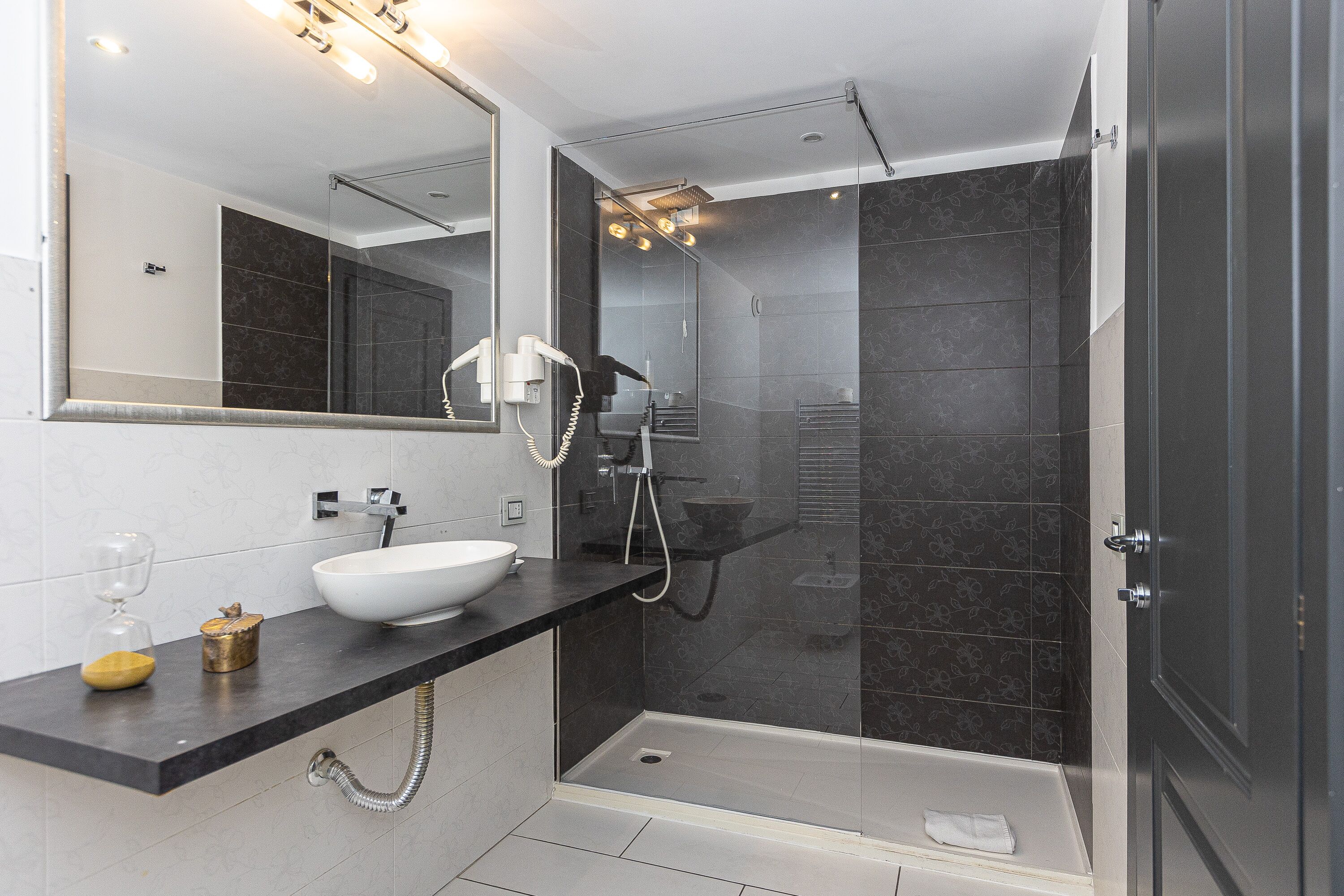 A modern bathroom with a large mirror, a white sink, and a glass-enclosed shower area.