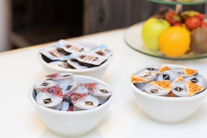 Three white bowls filled with packaged snacks on a table.