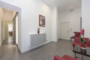 Un hall d’hôtel moderne avec un comptoir d’accueil, des sièges rouges et un tableau encadré au mur.
