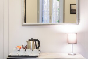 Una habitación de hotel con una mesa blanca, una cafetera y una lámpara.