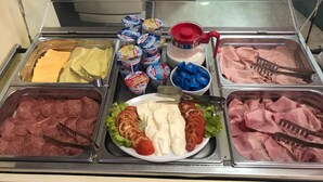 A buffet with various food items including meats, cheeses, and vegetables.