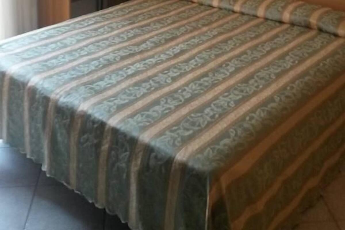 A bedroom with a bed, a desk, and a chair.