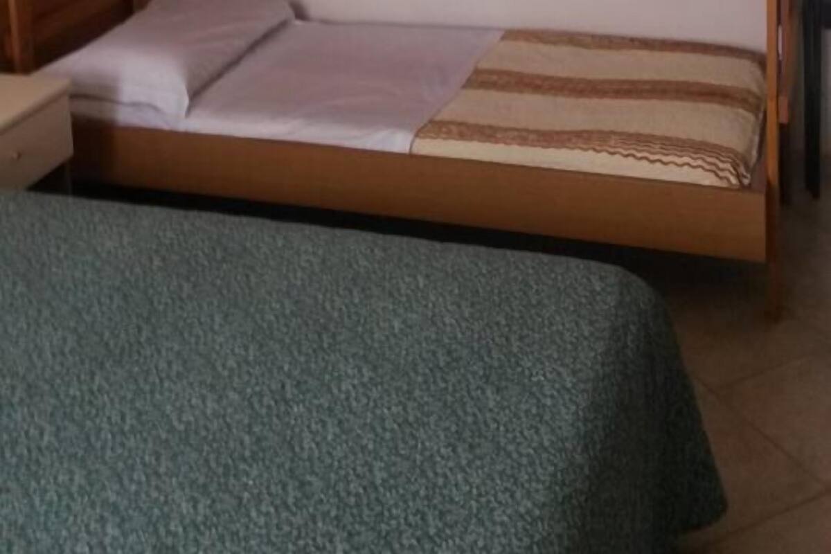 A bunk bed with a wooden frame and a lower bed with a green blanket.
