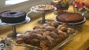 A buffet table with various desserts including cakes, pastries, and fruit.