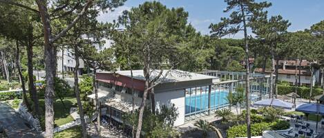 A resort with a swimming pool, outdoor seating, and surrounding trees.
