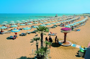 En la playa, playa de arena blanca, camastros y sombrillas 