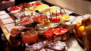 Een buffet met verschillende soorten eten, zoals fruit, kazen en gebak.